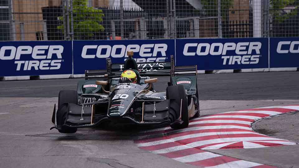 IndyCar on track with Cooper Tires signage in the background